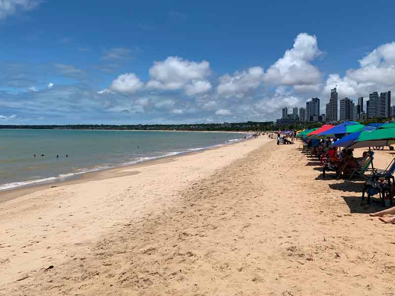 Areia de Tambaú, uma das praias de João Pessoa, com prédios ao fundo e guarda-sóis