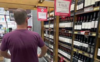 Homem com carrinho de mercado procura onde comprar vinho em Buenos Aires
