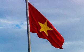 Bandeira do Vietnã em mastro com céu nublado