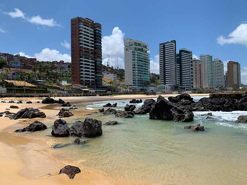 Piscinas naturais entre as pedras com grandes prédios de fundo em Areia Preta