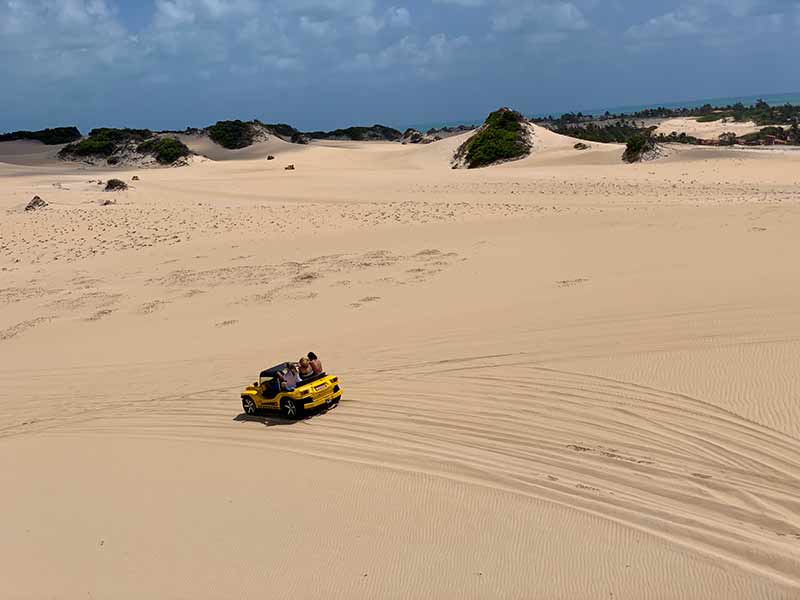 Buggy amarelo passa por areia durante passeio pelas Dunas de Genipabu, dica do que fazer em Natal