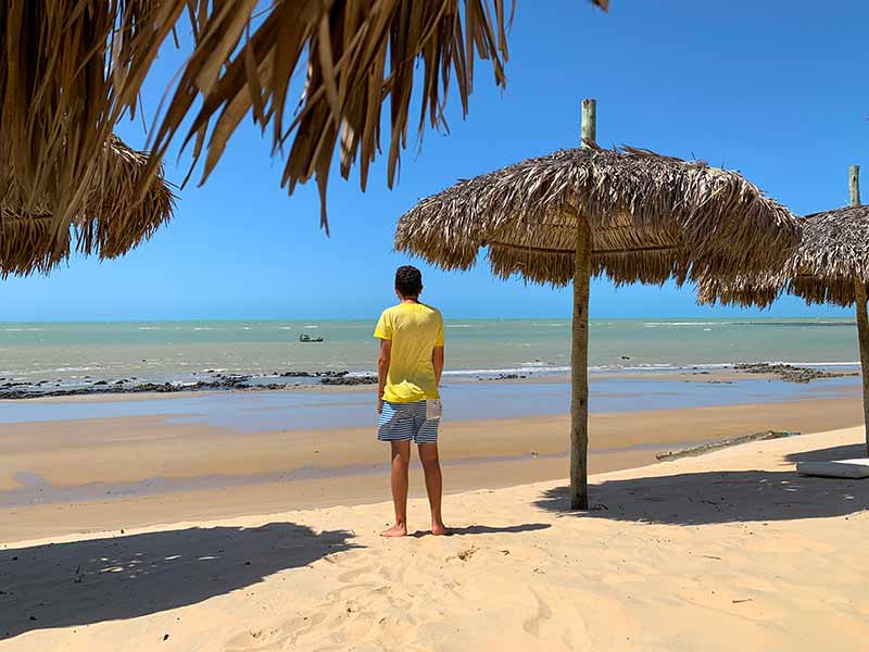 Homem em pé nas areias de uma praia em São Miguel do Gostoso em dia de céu azul
