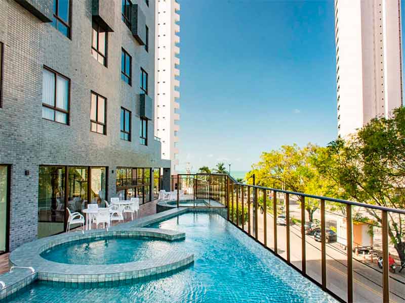 Piscina vazia do Ilusion, hotel em Natal, com prédio ao lado em dia de céu azul