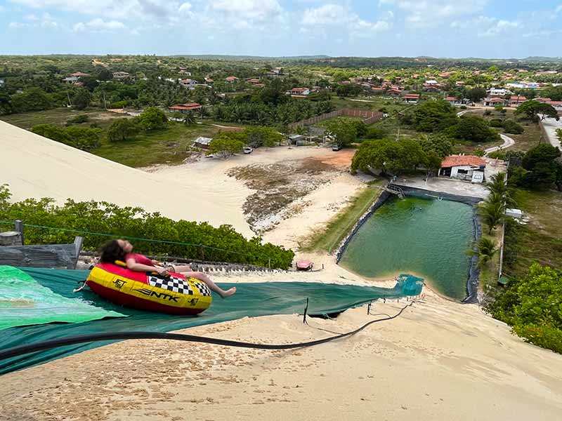 Mulher desce em boia numa lona na Lagoa de Jacumã, parada do tour pelas Dunas de Genipabu