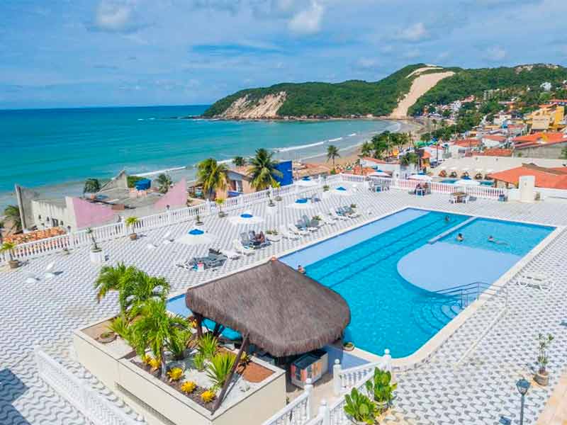 Área da piscina do Krisite Resort, dica de onde ficar em Natal, com vista para a praia e o Morro do Careca