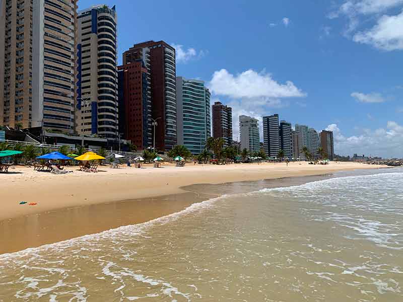 Grandes prédios vistos do mar e da areia com guarda-sóis de Miami, uma das praias de Natal