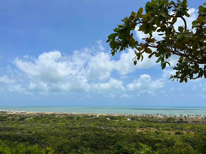 Vista do mar da praia de Pitangui em dia de céu azul com algumas nuvens