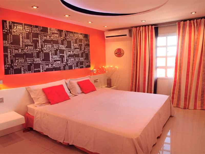 Quarto do Residence Village com tons avermelhados e cama de casal