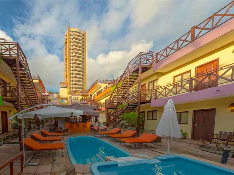 Piscina do Apart Hotel Serantes com espreguiçadeiras laranjas e prédio à frente