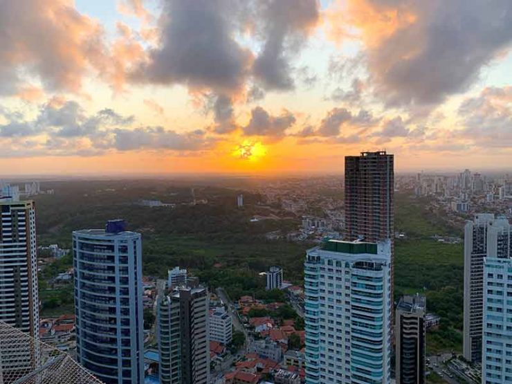 Pôr do sol lindo entre os prédios de João Pessoa com algumas nuvens no céu