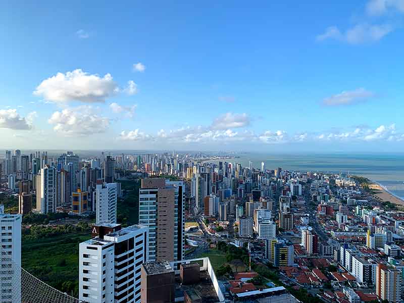 Vista do Skybar para os prédios e o mar de João Pessoa em dia de céu azul