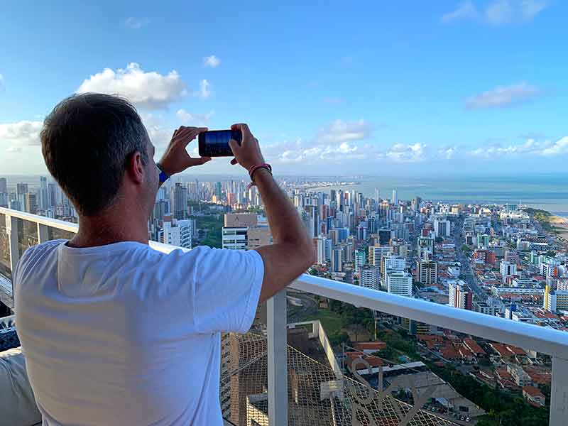 Homem tira foto dos prédios de João Pessoa no Skybar em dia de poucas nuvens