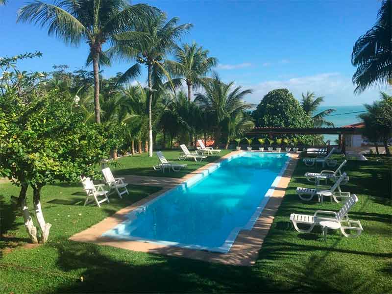 Área da piscina da Villa Simone em dia de céu azul e com espreguiçadeiras vazias