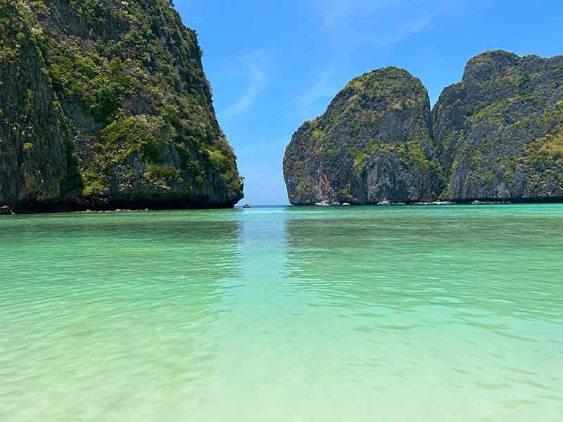 Mar esverdeado e vazio de Maya Bay com pedras ao fundo durante passeio de barco em Phi Phi