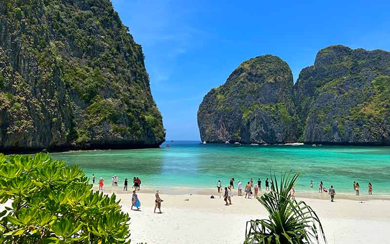 Vista de Maya Bay a partir de mirante com água esverdeada e pessoas na areia