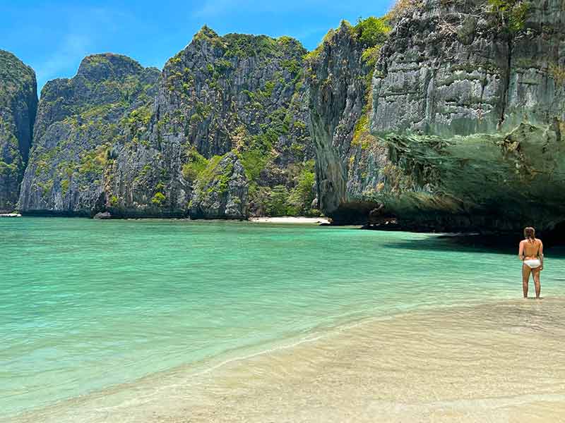 Mulher em pé em frente ao mar esverdeado de Maya Bay durante passeio de barco em Phi Phi