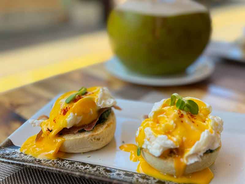 Ovos benedicts com água de coco ao fundo no Good Time Café