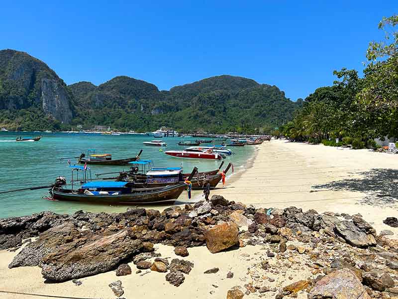 Barcos no mar claro e esverdeado de Phi Phi em dia de céu azul