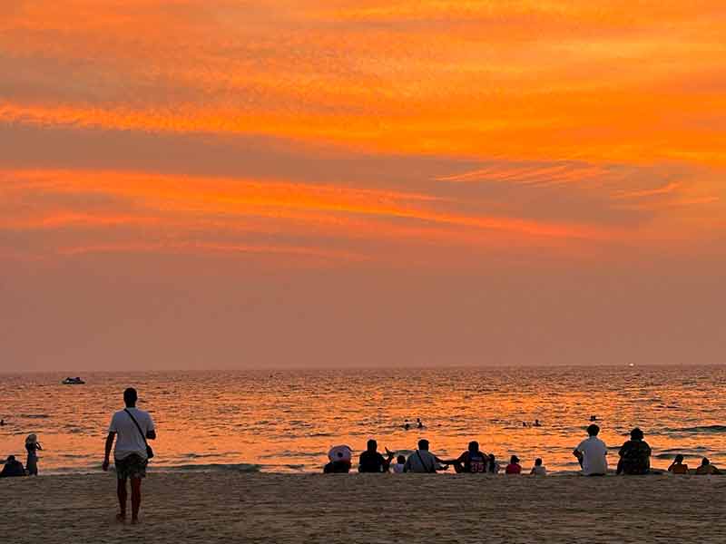 Homem caminha durante o pôr do sol em praia em Phuket, na Tailândia