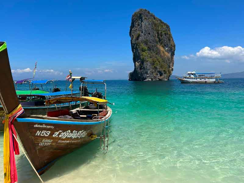 Barco parado no mar cristalino de Poda Island em dia de céu azul