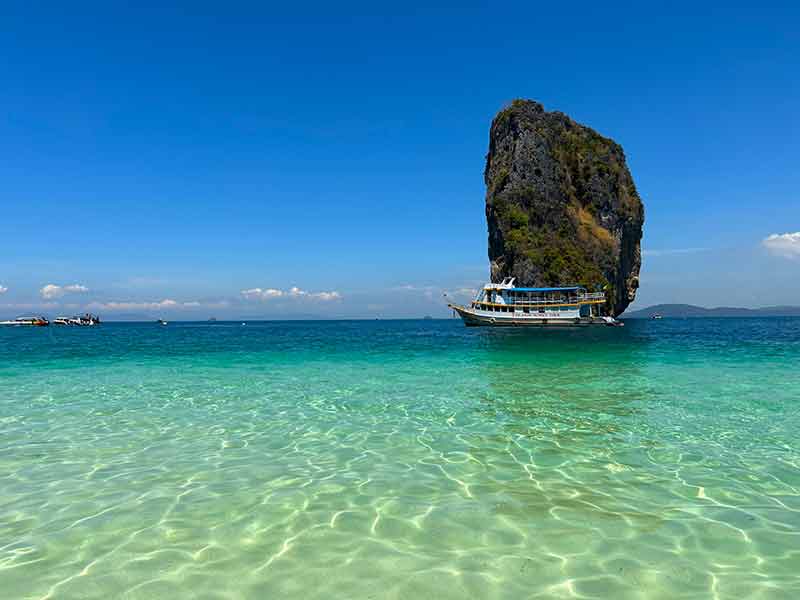 Mar vazio, cristalino e esverdeado da Poda Island, na Tailândia, com pedra ao fundo