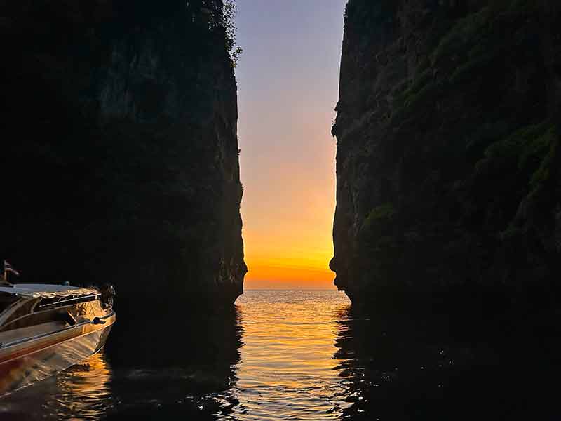 Céu amarelado pelo pôr do sol entre pedras no mar da Tailândia