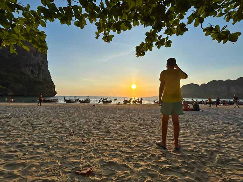 Homem em pé assiste ao pôr do sol em West Railay