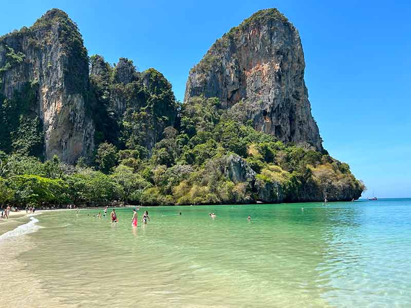 Mar vazio da West Railay, em Railay Beach, com pedras ao fundo em dia de céu azul