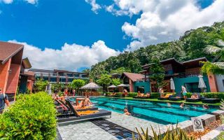 Turistas aproveitam piscina em dia de céu azul com nuvens no ChaoKoh Phi Phi