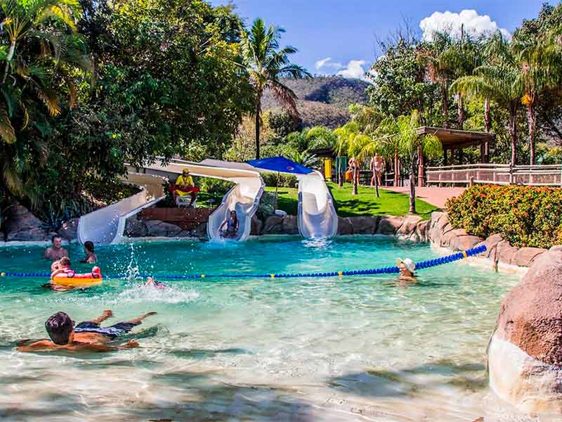 Três toboáguas caindo na piscina com pessoas na água do Acqua Race, no Hot Park, em Caldas Novas