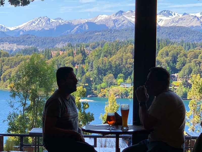 Homens almoçam com vista para o lago e montanhas na Cervejaria Patagonia