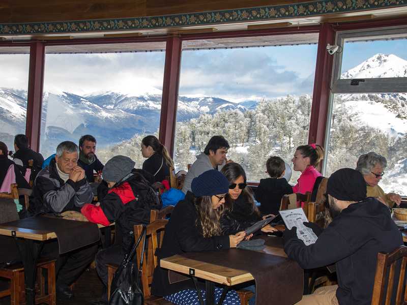 Turistas na Confeitaria Giratória de Bariloche com vista pras montanhas