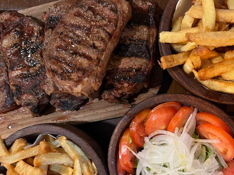 Bife de chorizo, batatas fritas e saladas vistas de cima no La Parrilla de Julián