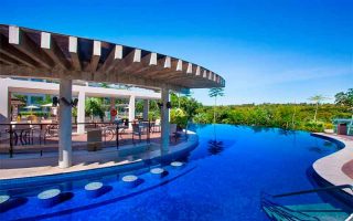 Piscina de borda infinita do Hotel Cristal, dica de onde ficar em Rio Quente, com vegetação e céu sem nuvens