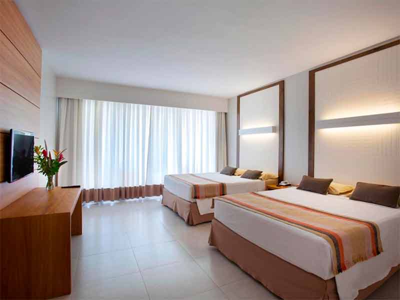 Quarto do Hotel Cristal, do Rio Quente Resorts, com duas camas de casal, TV e decoração clara