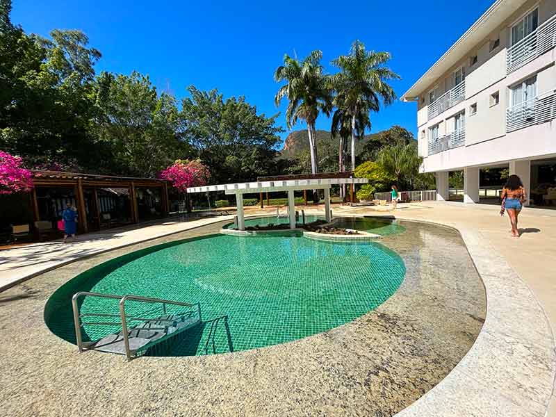 Mulher caminha na área da piscina do Hotel Turismo em dia de céu azul