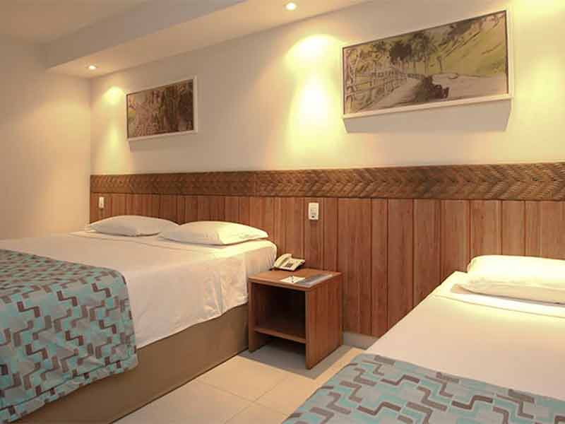 Quarto do Hotel Turismo, próximo ao Hot Park, com duas camas e quadros na parede