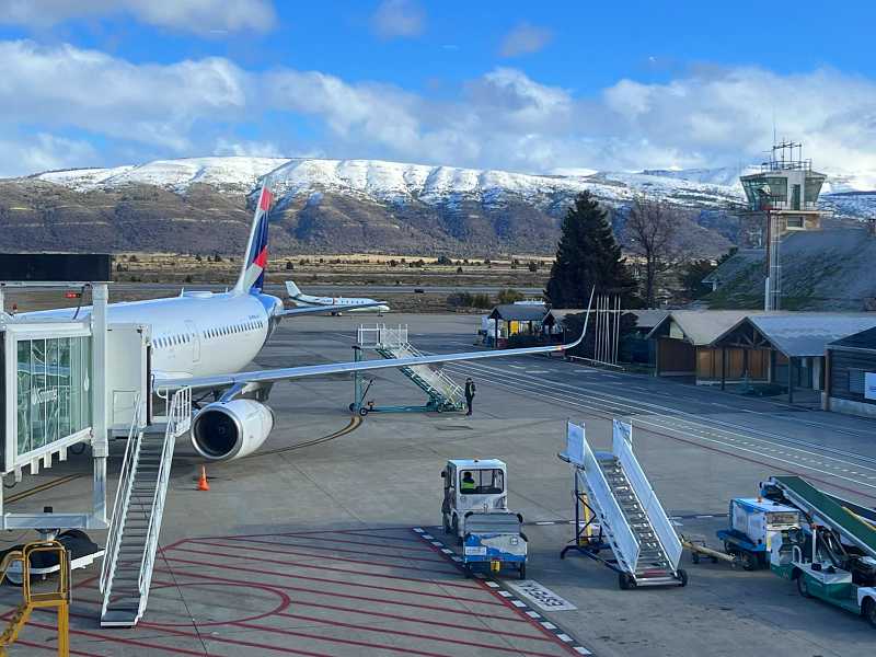 Avião na pista do aeroporto de Bariloche com montanhas nevadas ao fundo