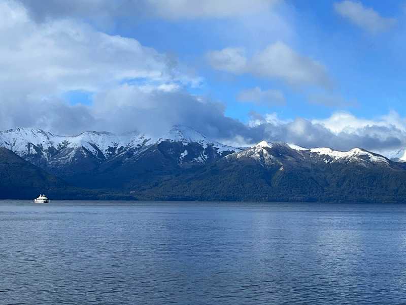 Barco no Lago Nahuel Huapi com montanhas com neve ao fundo