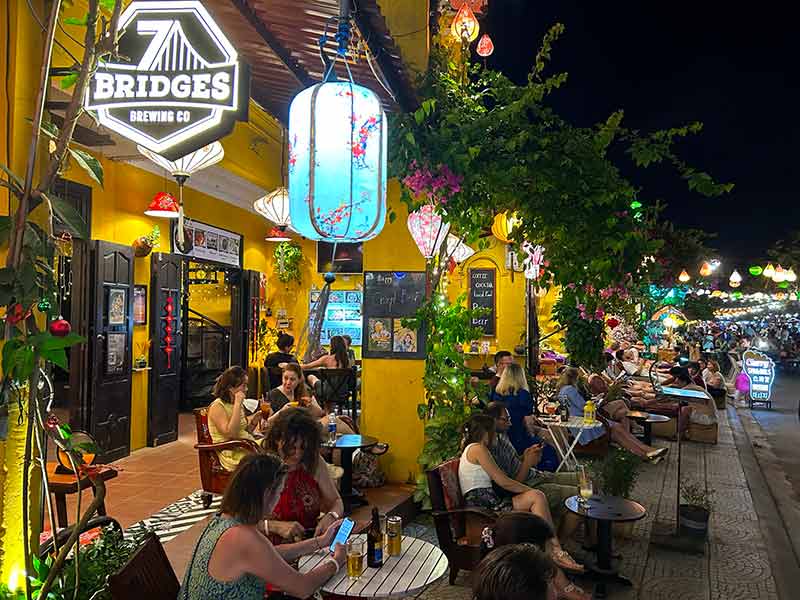 Pessoas sentadas ao ar livre em bar bebendo e conversando à noite, dica de o que fazer em Hoi An