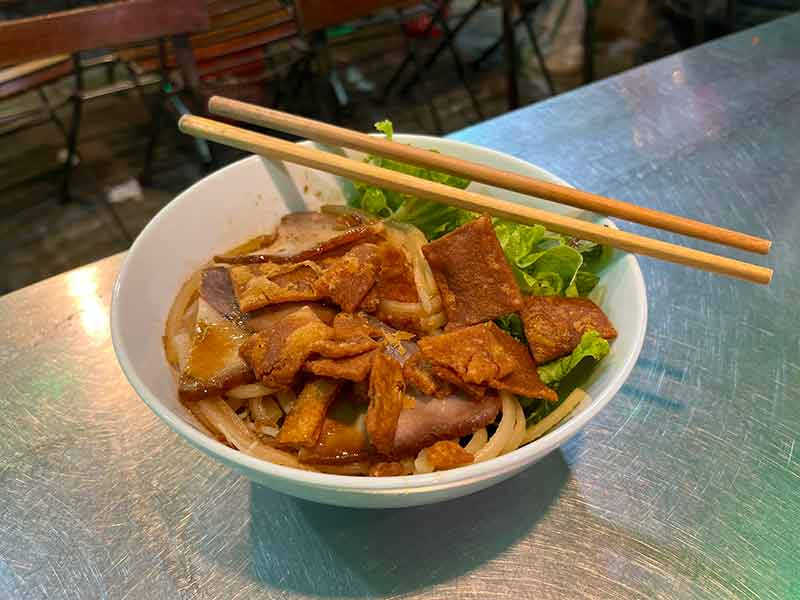 Hashi em cima de cumbuca com cao lau, macarrão com carne de porco e legumes, dica de onde comer em Hoi An