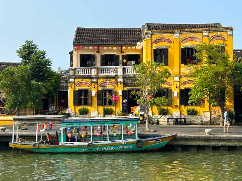 Barco parado em frente à antiga construção amarela, dica de o que fazer em Hoi An
