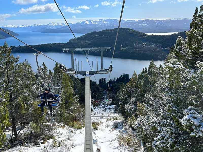 Pessoa subindo no teleférico do Cerro Campanário com muita neve no chão