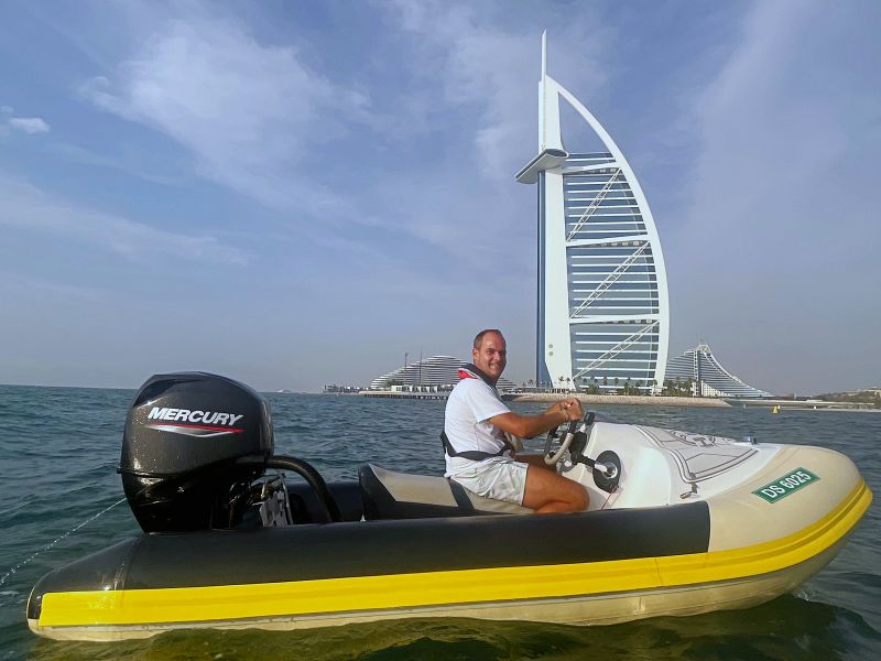 Homem pilota barco da Hero Boat Tour em frente ao Burj Al Arab