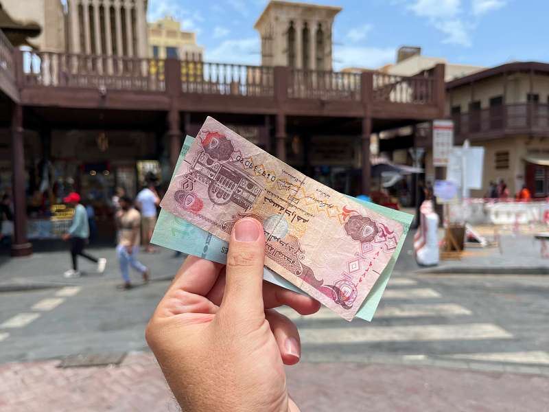 Mão segura cédulas de dirham, moeda dos Emirados Árabes Unidos