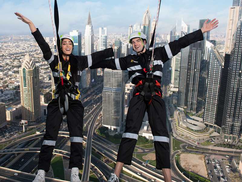 Casal caminha do lado de fora do Skyviews com cidade ao fundo