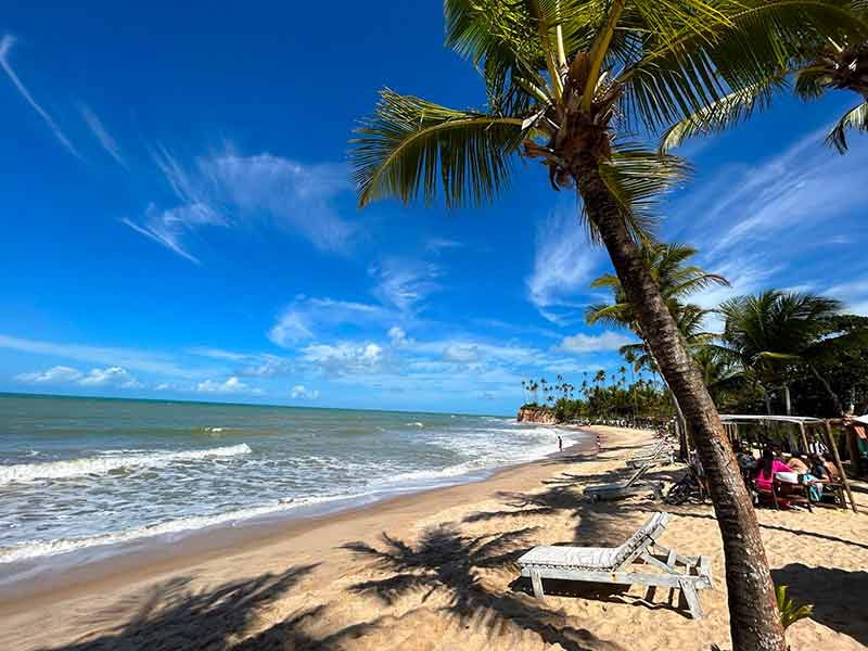 Praia da Barra do Cahy com mar e areias vazias e coqueiros