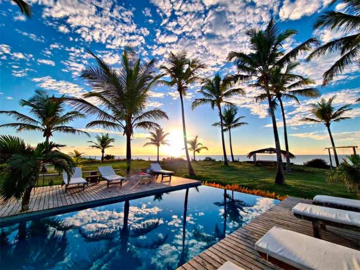 Vista da piscina de borda infinita da Vila Bella Vista, dica de onde ficar em Corumbau, com sol, coqueiros e mar
