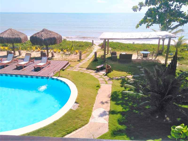 Piscina vazia da pousada Mayon com espreguiçadeiras e vista para o mar