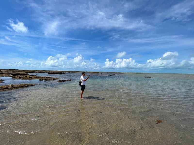Homem fotografa piscinas naturais na Praia do Moreira, na Bahia